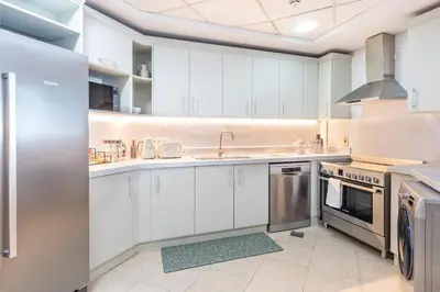 a kitchen with white cabinets and stainless steel appliances at BURJ views Private Beach 2 Bedroom Apartment with panoramic Sea View and Pool Palm Jumeirah in Dubai