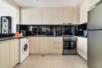 a kitchen with white cabinets and a washer and dryer at GuestReady - Modern living in JVC in Dubai