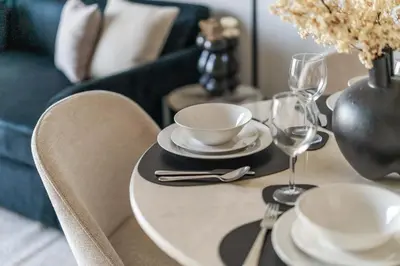 a table with plates and glasses on a table with a blue couch at GuestReady - Modern living in JVC in Dubai