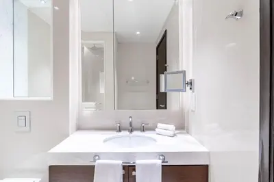 a white bathroom with a sink and a mirror at The ME Apartment in Dubai