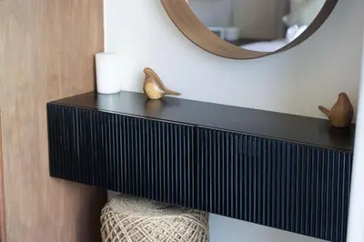 a black shelf on a wall with a mirror at Lake View Studio near Marina with Pool, Sauna and Gym in Dubai
