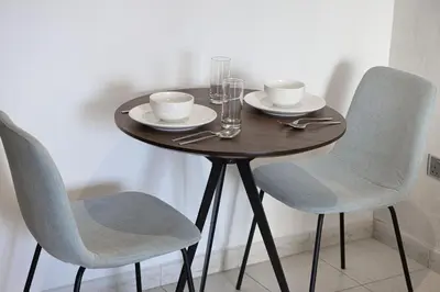 a wooden table with two chairs and a table with plates and cups at Lake View Studio near Marina with Pool, Balcony and Gym in Dubai