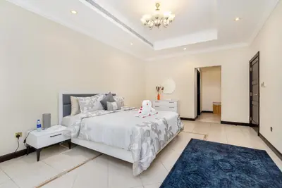 a bedroom with a white bed and a blue rug at Samaya Holiday Homes - Luxury Villa Pool - Beach Access & Fishing Zone in Dubai