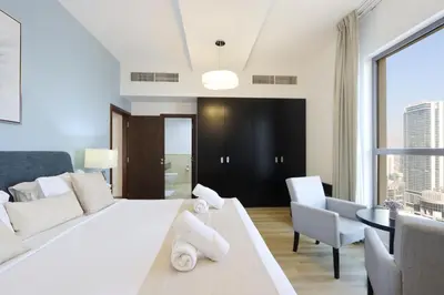 a bedroom with a large white bed and a couch at Livbnb- Coastal 2B with Marina View Walk to Beach in Dubai