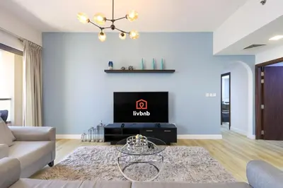 a living room with a couch and a tv at Livbnb - High Floor 2B with Marina View Walk to Beach in Dubai