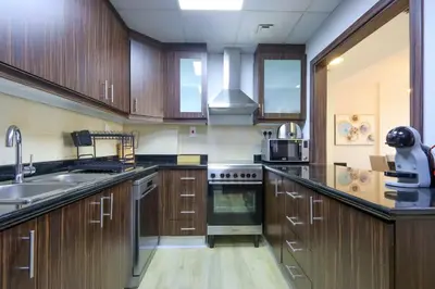 a large kitchen with wooden cabinets and a sink at Livbnb - High Floor 2B with Marina View Walk to Beach in Dubai