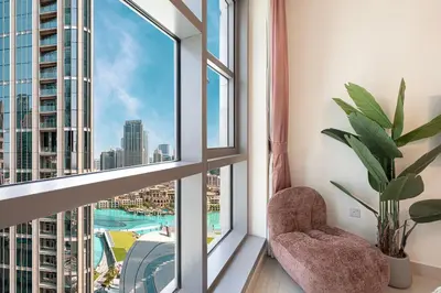 a room with a window with a chair and a plant at Splendid 2BR Burj Khalifa & Fountain view in Dubai