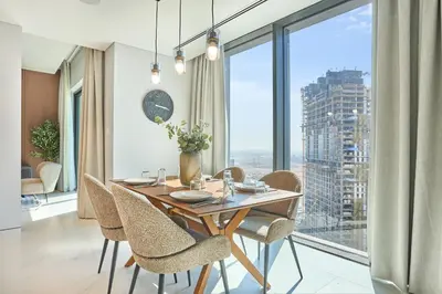 a dining room with a table and chairs and a large window at STAY BY LATINEM Luxury 1BR Holiday Home CVG 2409 Near Burj Khalifa in Dubai