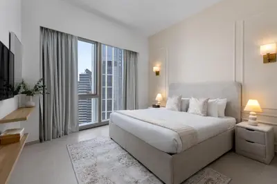 a white bedroom with a large bed and a large window at Maison Privee - Sky-High Elegance with Unrivaled Burj Khalifa Views in Dubai
