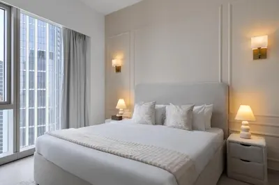 a white bedroom with a large bed and a large window at Maison Privee - Sky-High Elegance with Unrivaled Burj Khalifa Views in Dubai