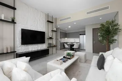 a living room with white furniture and a flat screen tv at Maison Privee - Sky-High Elegance with Unrivaled Burj Khalifa Views in Dubai