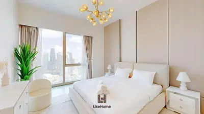 a bedroom with a white bed with a chandelier at Enjoy Best Burj Khalifa & Fountain Views From Balcony Luxury 2BR 3 Mins from Dubai Mall - Like Home in Dubai