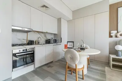 a kitchen with white cabinets and a white table and chairs at GuestReady - Luxe Residence in Dubai Marina in Dubai
