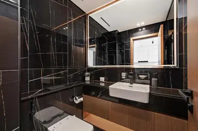a black tiled bathroom with a toilet and a sink at Luxury 1BR at Binghatti Onyx JVC in Dubai