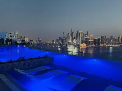 a swimming pool with a city skyline in the background at Seven Palm Apartment with Private Beach Access and Infinity Pool in Dubai