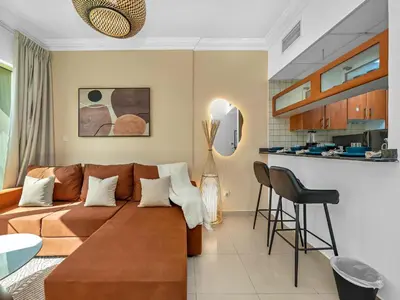 a living room with a brown couch and a kitchen at Luxurious Home in the heart of Dubai Marina in Dubai
