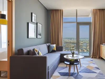 a living room with a blue couch and a table at Private Apartment in Novotel JVT Comfort for 4 Guests in Dubai