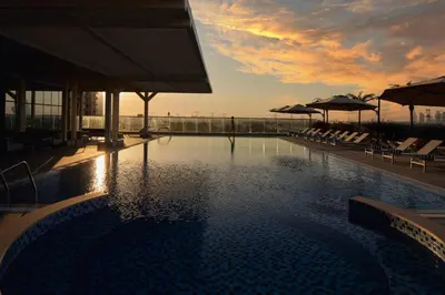 a swimming pool with chairs and umbrellas on a building at Private Apartment in Novotel JVT Comfort for 4 Guests in Dubai