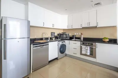 a kitchen with white cabinets and a washer and dryer at Frank Porter - Laguna Tower in Dubai