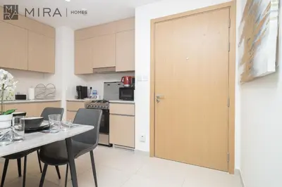 a kitchen with a table and chairs and a wooden door at Mira Holiday Homes - Cosy 1BHK in the heart of Dubai Creek Harbour in Dubai