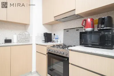 a kitchen with a stove and a microwave at Mira Holiday Homes - Cosy 1BHK in the heart of Dubai Creek Harbour in Dubai