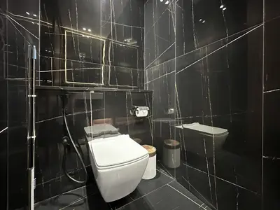 a bathroom with a toilet and a black tiled wall at Trophy-Cultivate Retreat with Statement Design in Dubai