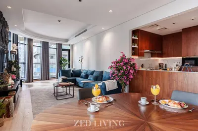 a living room with a table and a kitchen at RP Heights - Luxe 2BR with Burj Khalifa View - Zed Living in Dubai