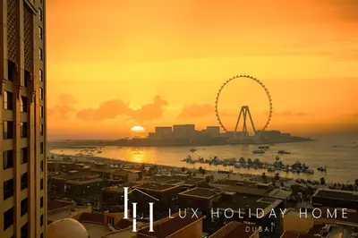 a view of a beach with a ferris wheel at sunset at LUX The Dubai Eye View JBR Studio in Dubai