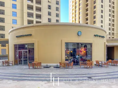 a building with tables and chairs in front of some buildings at LUX The Dubai Eye View JBR Studio in Dubai