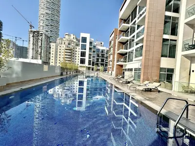 a large swimming pool in a city with buildings at Homes2Retreat - Stylish Studio Gym & Pool, JVC Dubai in Dubai