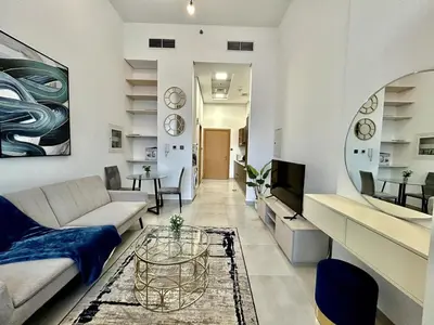 a living room with a couch and a table at Homes2Retreat - Stylish Studio Gym & Pool, JVC Dubai in Dubai