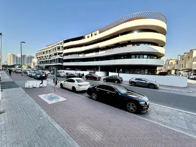a parking lot with cars parked in front of a building at Homes2Retreat - Stylish Studio Gym & Pool, JVC Dubai in Dubai
