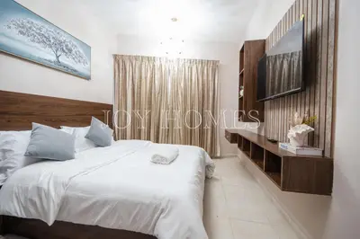 a bedroom with a white bed and a tv at Amiralty Easy Stay in Dubai