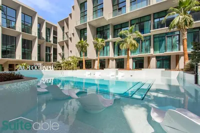 a swimming pool in front of a building with palm trees at Studio in The Autograph JVC w amazing facilities in Dubai