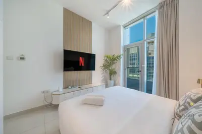 a white bedroom with a large bed and a tv at Stunning Views Spacious 3BR Dubai Marina in Dubai
