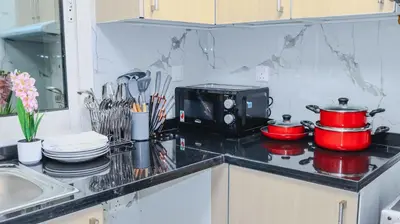 a kitchen counter with a stove with pots and pans at 1BHK Homes For Holidays in Dubai