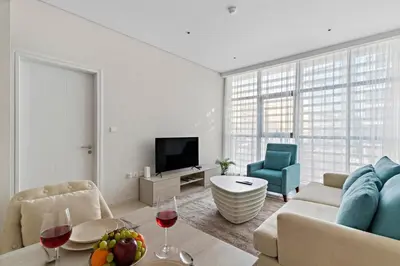 a living room with a couch and a table with wine glasses at 1BR Apartment on The Palm Walk to Beach Mall Pool Restaurants in Dubai