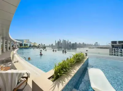 a large swimming pool with people in the water at 1BR Apartment on The Palm Walk to Beach Mall Pool Restaurants in Dubai