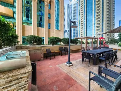a patio with tables and chairs and a hot tub at Cozy 1 Bedroom in Elite Residence in Dubai