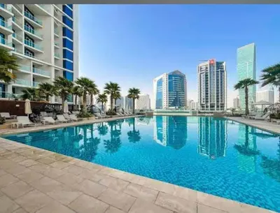 a large swimming pool with palm trees and buildings at Luxury Studio Apartment Canal View Near Dubai Mall in Dubai