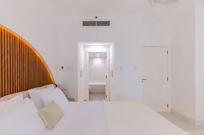 a bedroom with a white bed with a wooden headboard at Luxury One-Bedroom Burj Khalifa in Dubai