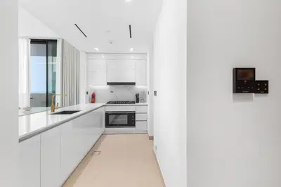 a white kitchen with white cabinets and a long hallway at Your Own Pool Spacious 2BDR Apartment JVC in Dubai