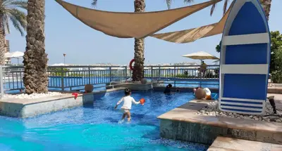 a person in a swimming pool with a surfboard at Bright Beachfront Studio with Breathtaking Views in Dubai