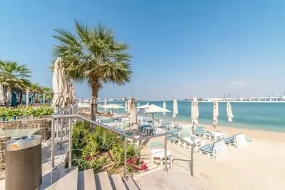 a beach with chairs and umbrellas and the ocean at Bright Beachfront Studio with Breathtaking Views in Dubai