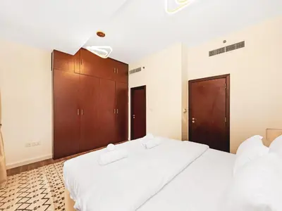 a bedroom with two white beds and wooden cabinets at New! JBR Beachfront with Panoramic Dubai Eye Views in Dubai