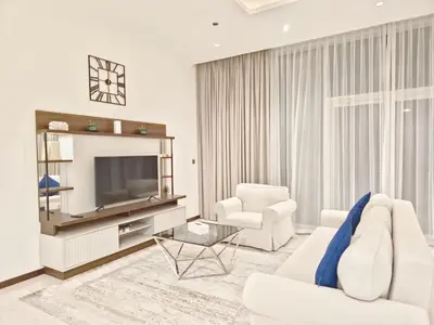 a living room with a white couch and a television at The Palm Panorama Chic Apartment with Open Sea Views Managed by SunnyHomes in Dubai