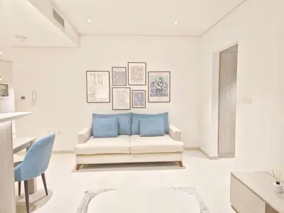 a living room with a white couch and blue pillows at The Palm Hideaway Chic Apartment with Rooftop Vibes Managed by SunnyHomes in Dubai