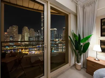 a room with a view of a city at night at Cozy Home w Spectacular Water View in Dubai