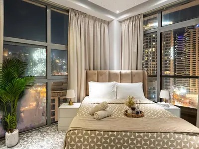 a bedroom with a large bed with large windows at Luxurious 2BR Apt with Marina View & Private Jacuzzi in Dubai