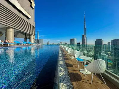 a swimming pool with chairs and a view of the city at Sky Suite 1 Bedroom Apartment with Infinity Rooftop Pool and Dubais Ultimate Skyline View at Paramount Midtown in Dubai